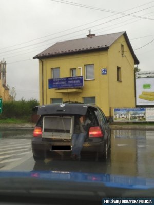 Samochód z otwartym bagażnikiem. Wewnątrz lodówka i człowiek